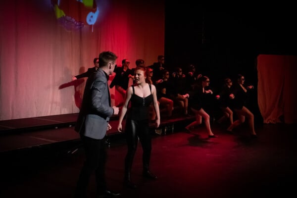 Performing Arts learners performing on stage with dancers behind them