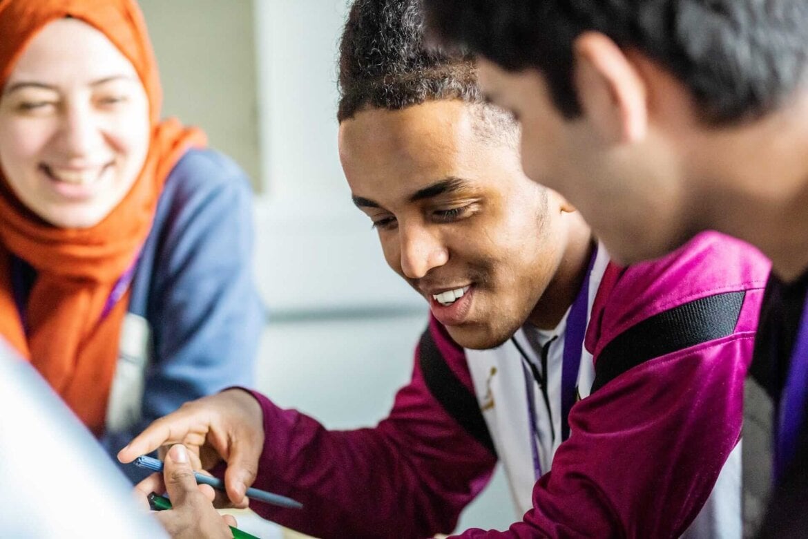 group of students holding pens writing on paper