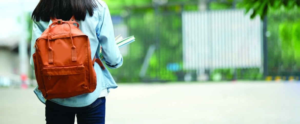 Student wearing a backpack, holding books.