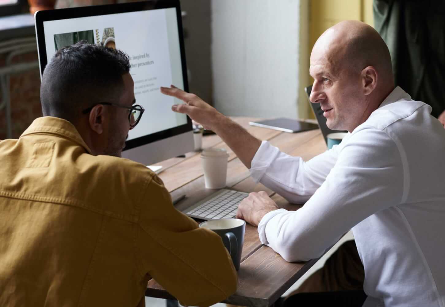 Two people discussing at desktop with a computer