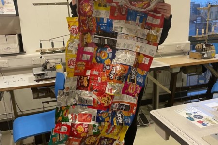 Fashion student displaying sleeping bag made from crisp packets