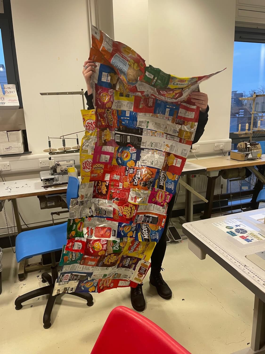 Fashion student displaying sleeping bag made from crisp packets