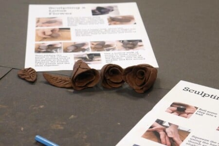 Clay flowers on bench with leaflets
