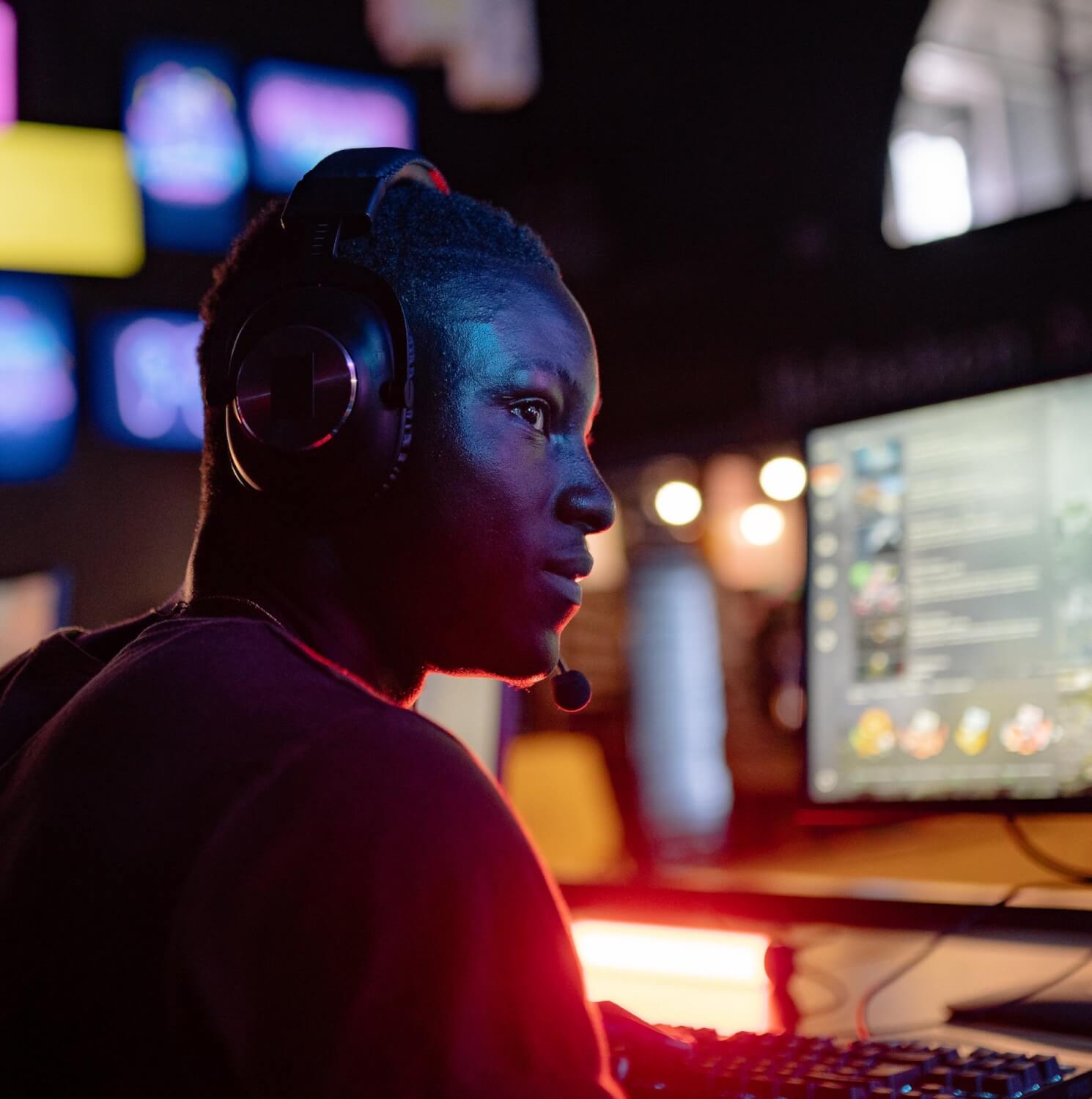 man sitting at gaming computer wearing gaming headset with game on screen