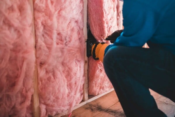 worker applying spray foam to wall cavity