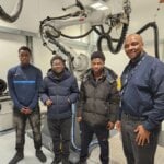 Engineering Students standing in front of equipment during a visit to the AME Centre