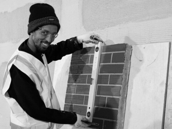 Male construction worker wearing high visibility vest holding spirit level to wall