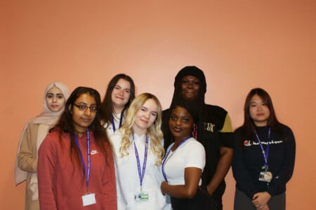 Group of Health and Social Care students standing in front of an orange background