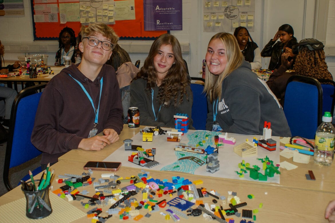 Three health and social care learners sat at desk in front of a table full of Lego