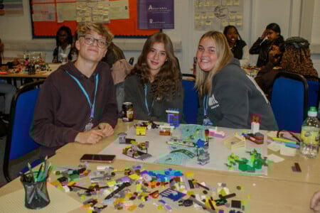 Three health and social care learners sat at desk in front of a table full of Lego