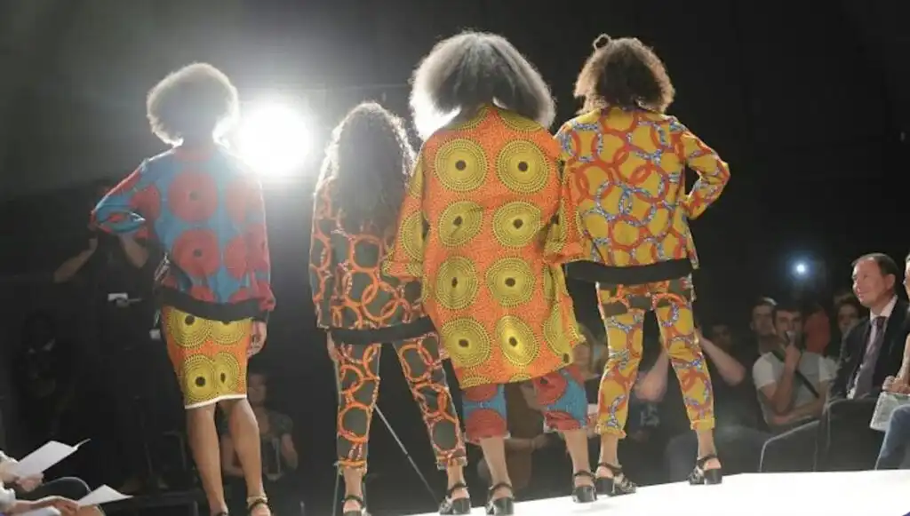 Four young people wearing flowery clothes at fashion show with back to camera