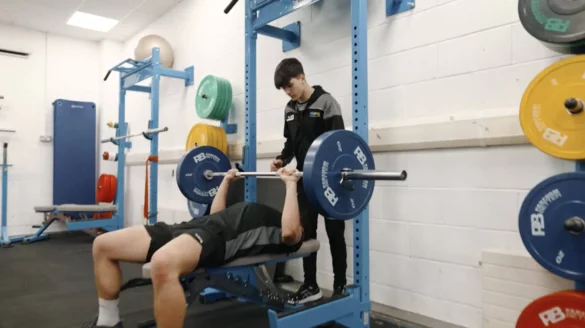 Person in a gym bench pressing with person spotting them